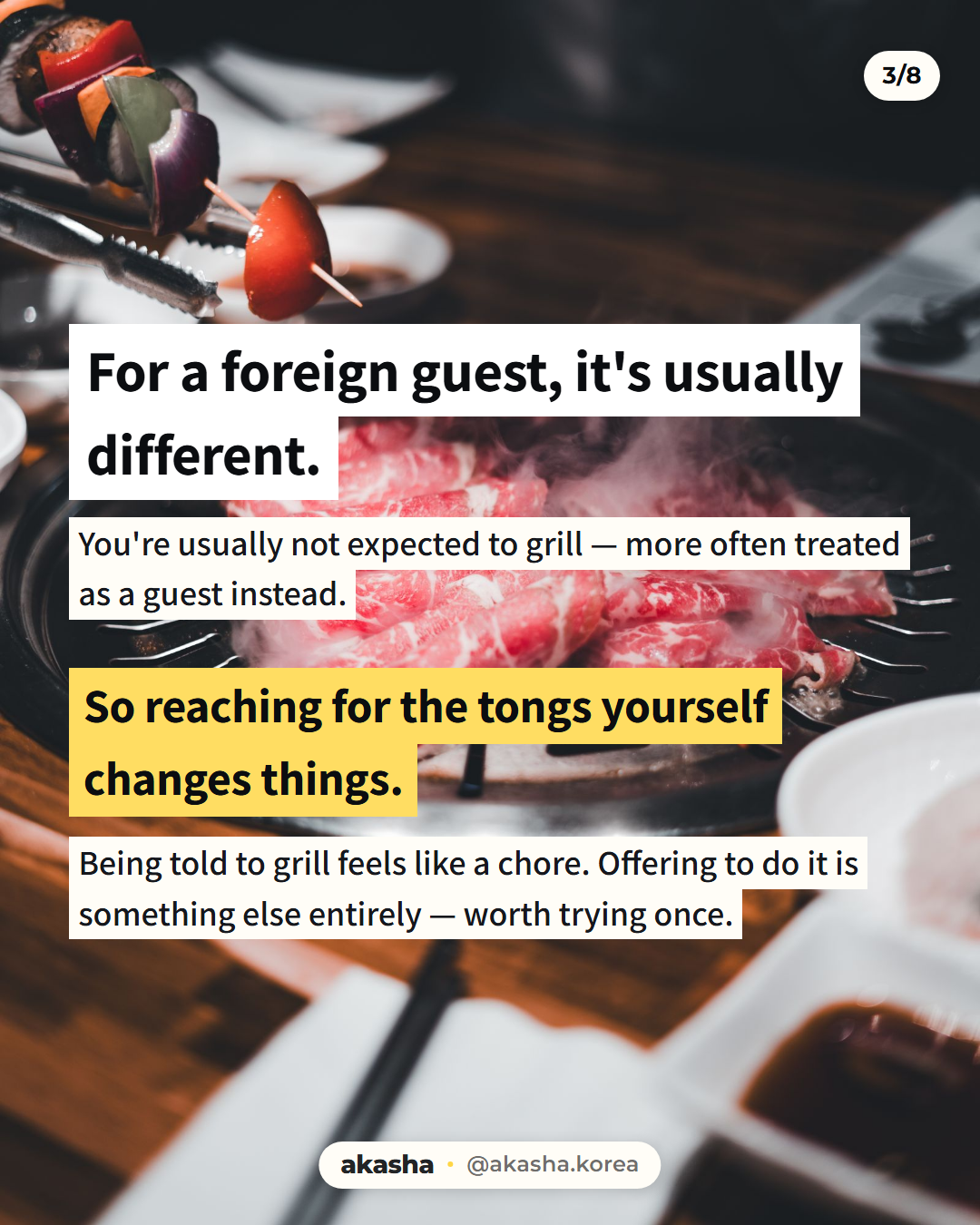 Metal tongs holding a vegetable skewer above a round Korean grill with thin marbled beef smoking on it, under the line For a foreign guest, it's usually different